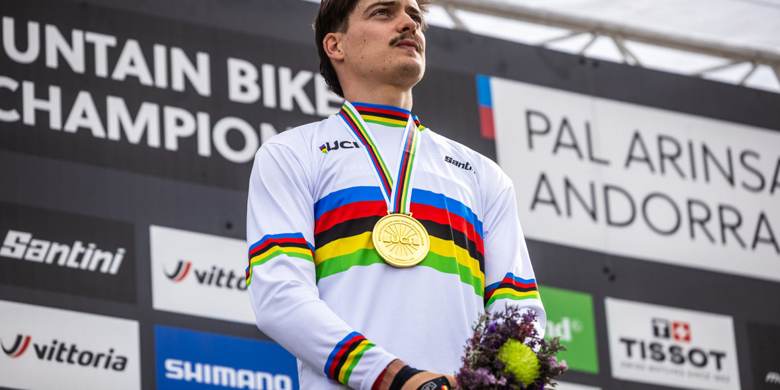 loris vergier champion du monde 2024 de descente vtt dhi sur le podium avec son maillot et sa médaille
