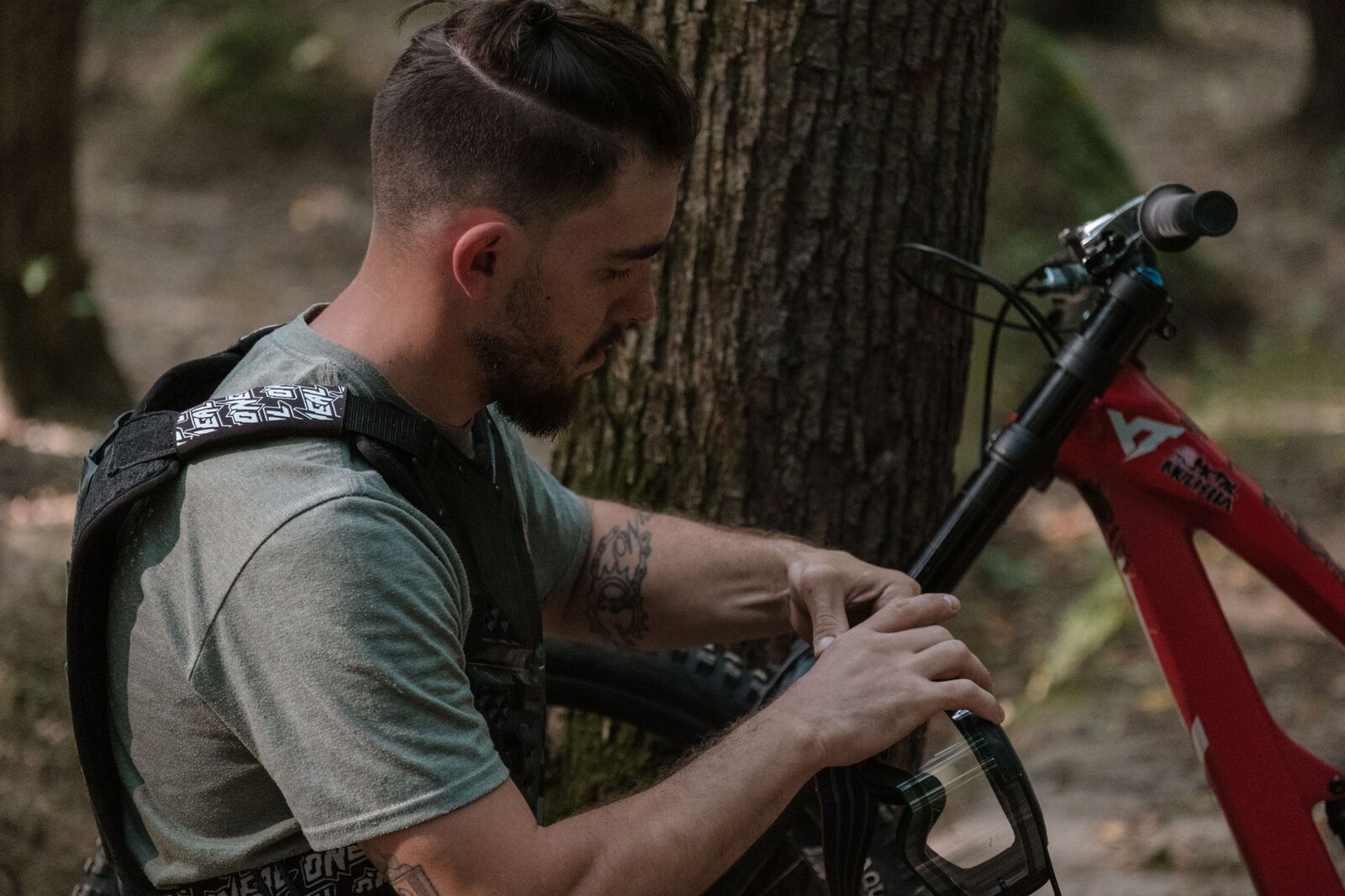 Vététiste vérifiant son vélo dans une forêt