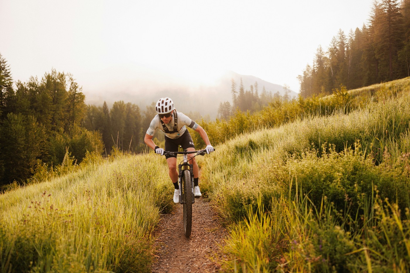 Vététiste en pleine progression sur un singletrack accidenté en forêt