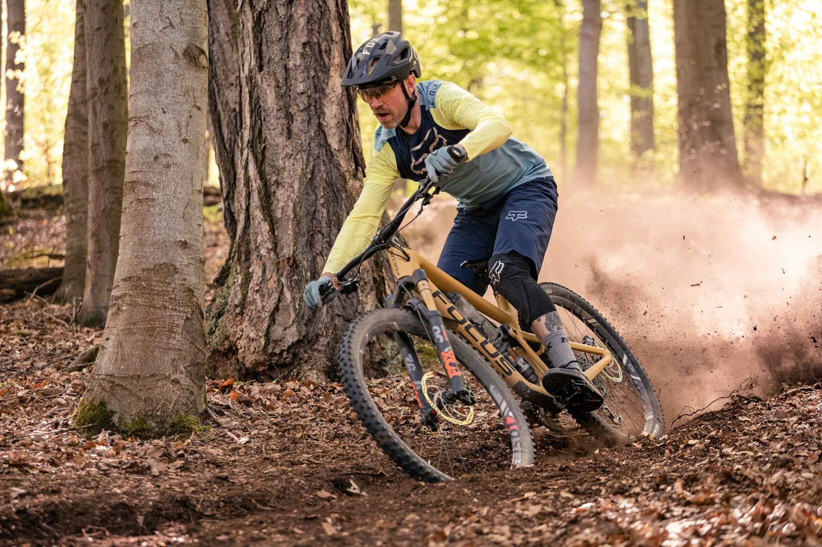 Un vététiste casqué en action sur un sentier technique en sous-bois